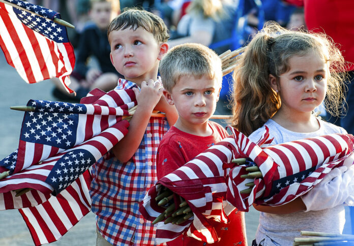 Brayden Austin, left, Gavin Colby, middle, and Brylee Roberge patiently wait with an armful of flags to be burned Tuesday at Veterans Memorial Park in Lewiston, Maine. Photo: Russ Dillingham / Associated Press