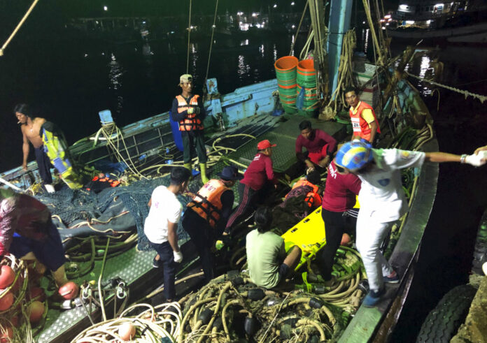Rescued tourists from a boat that sank are helped onto a pier from a fishing boat Thursday on Phuket. Photo: Associated Press