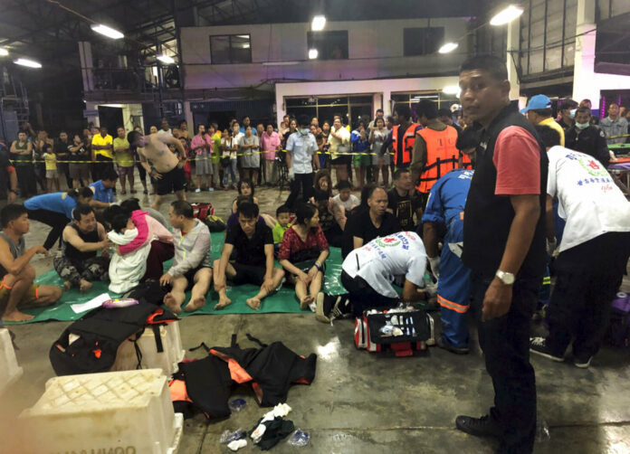 Rescued tourists from a boat that sank rest on a pier Thursday, July 5, 2018, on the island of Phuket. Photo: Thailand Royal Police via Associated Press