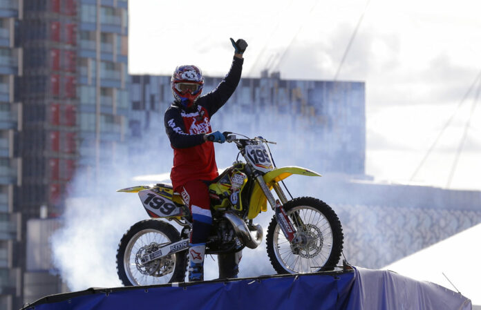 Nitro Circus ringleader and stunt professional Travis Pastrana celebrates Oct. 5, 2017, after he performed the first motorcycle backflip over the River Thames with a 75-foot wide gap between two floating barges, in London. Photo: Alastair Grant/ Associated Press File