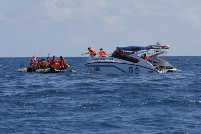 Thai rescue divers and a tourist police boat are seen Saturday during a search mission for missing passengers from a capsized tourist boat in the water off Phuket. Photo: Vincent Thian / Associated Press