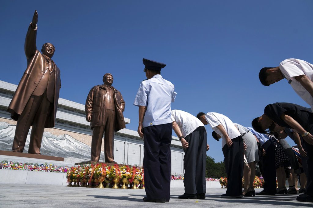 People pay their respects Saturday in front of bronze statues of the late leaders Kim Il Sung, left, and Kim Jong Il at Munsu Hill in Pyongyang, North Korea. Photo: Andrew Harnik / Associated Press