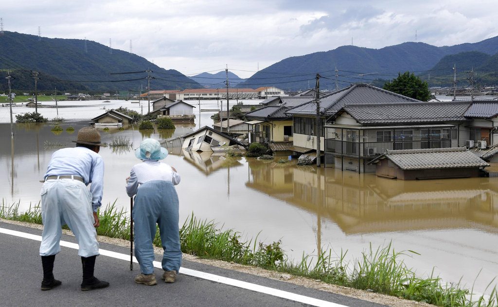 Residents look at half submerged houses Sunday in floodwater from heavy rains, in Kurashiki, Okayama prefecture, southwestern Japan. Photo: Koji Harada / Associated Press