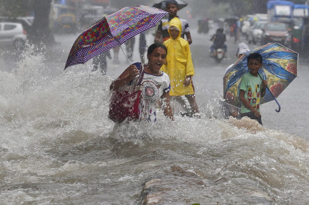 A woman walking through a water-logged street, reacts as a truck driving past creates a wave of ripples prior to drenching her during monsoon rains, Sunday in Mumbai, India. Photo: Rafiq Maqbool / Associated Press