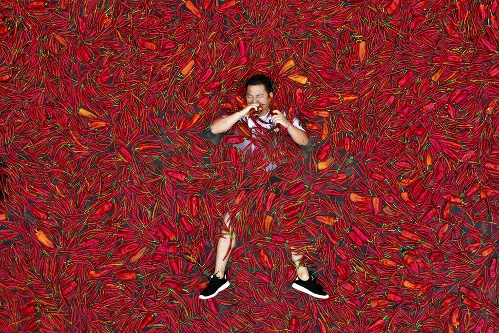 A contestant lies on a pool of red chilies Sunday as he takes part in a chili eating competition in Ningxiang in China's central Hunan province. Photo: Associated Press