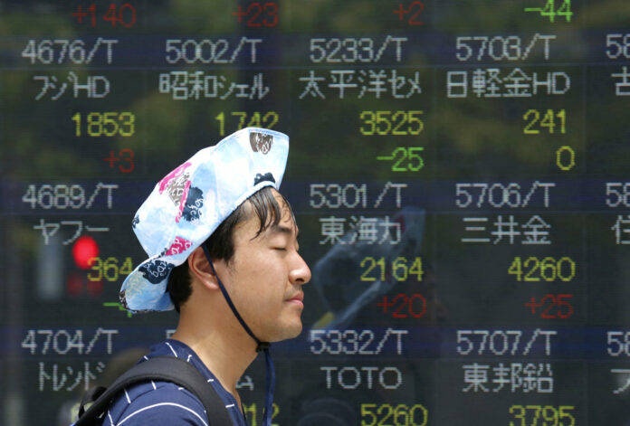 A man walks by an electronic stock board of a securities firm in July in Tokyo, Japan. Photo: Koji Sasahara / Associated Press
