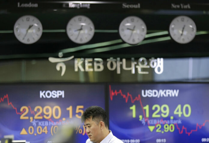 A bank employee stands near screens showing the Korea Composite Stock Price Index (KOSPI), left, and the foreign exchange rate between U.S. dollar and South Korean won at the foreign exchange dealing room in July in Seoul, South Korea. Photo: Lee Jin-man / Associated Press