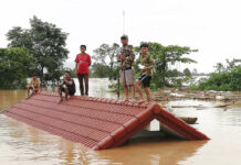 Flooding From Laos Hydroelectric Dam Leaves Hundreds Missing Villagers take refuge on a rooftop above flood waters from a collapsed dam Tuesday in the Attapeu district of southeastern Laos. Photo: Associated Press