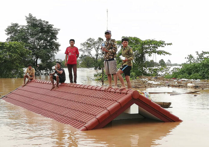 Villagers take refuge on a rooftop above flood waters from a collapsed dam Tuesday in the Attapeu district of southeastern Laos. Photo: Associated Press