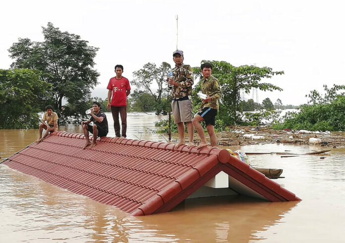 Villagers take refuge on a rooftop above flood waters from a collapsed dam Tuesday in the Attapeu district of southeastern Laos. Photo: Associated Press Villagers take refuge on a rooftop above flood waters from a collapsed dam Tuesday in the Attapeu district of southeastern Laos. Photo: Associated Press