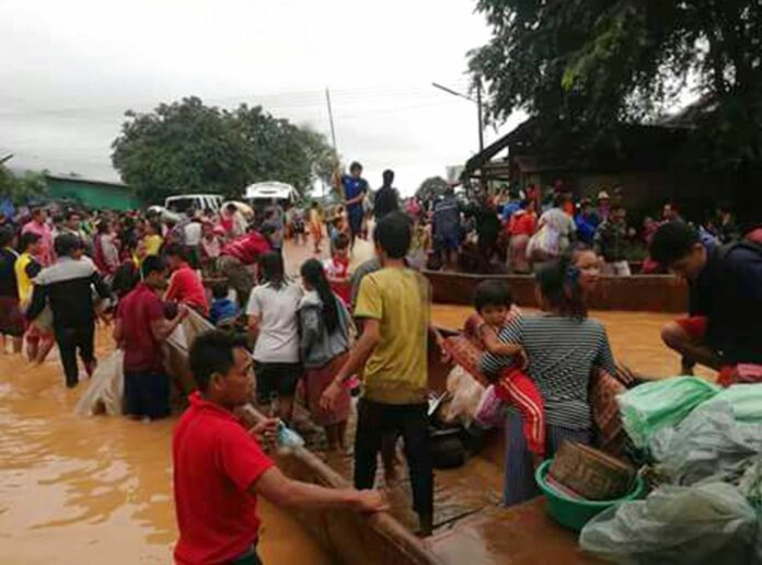 People on Tuesday are evacuated through the floodwaters from a collapsed dam in southeastern Laos. Image: Associated Press