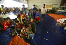 Questions Raised as Villages Dig out From Laos Dam Collapse Villager Phon Vuongchonpu and his grandchildren take refuge at a shelter Wednesday in Paksong town, Champasak province, Laos. Photo: Hau Dinh / Associated Press