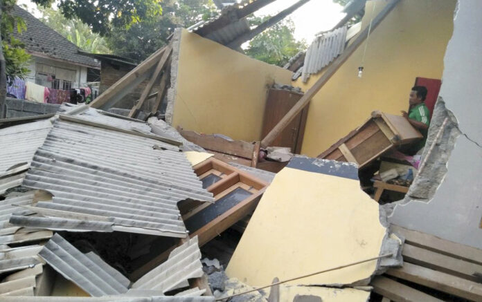 In this image made from video released by Indonesia's Disaster Mitigation Agency, a man inspects the damage caused by an early Sunday morning earthquake on the island of Lombok, Indonesia. Photo: Indonesia's Disaster Mitigation Agency via AP