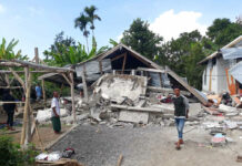 Strong Quake Hits Indonesian Island, Killing at Least 14 Villagers walk near destroyed homes in an area affected by the early Sunday morning earthquake at Sajang village, Sembalun, East Lombok, Indonesia. Photo: Rosidin / Associated Press