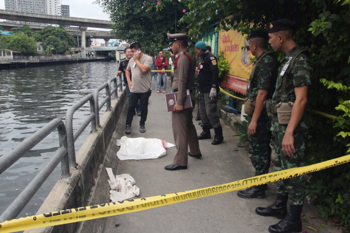 A police officer Sunday investigates the scene near Khlong Saen Saep where part of a human body was found.