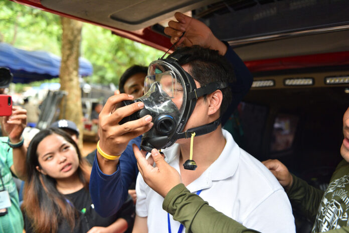 A man tries on a full-face diving mask Tuesday at Tham Luang Nang Non.