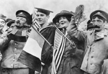 Prayuth Invited to Celebrate Armistice Centennial in France Armistice Day Celebrations, Paris, Nov. 11 1918. An American sailor, an American Red Cross Nurse and two British soldiers celebrating the signing of the Armistice, near the Paris Gate at Vincennes, Paris. Photo: Imperial War Museum