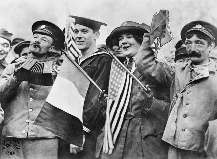 Armistice Day Celebrations, Paris, Nov. 11 1918. An American sailor, an American Red Cross Nurse and two British soldiers celebrating the signing of the Armistice, near the Paris Gate at Vincennes, Paris. Photo: Imperial War Museum