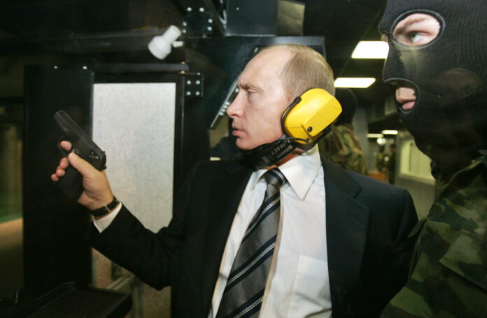 In this 2006 file photo, President Vladimir Putin wears headphones as he tests a pistol in a shooting range as he visits the Defense Ministry's Main Intelligence Directorate in Moscow, Russia. Dmitry Astakhov / Sputnik via AP