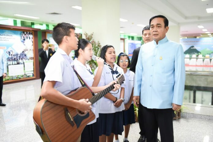 Junta chairman Prayuth Chan-ocha poses for photos Thursday with a group of young musicians in Bangkok.