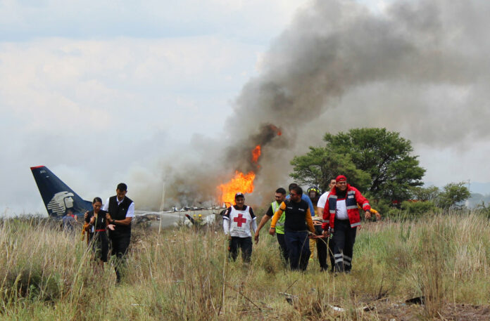 In this photo released by Red Cross Durango communications office, Red Cross workers and rescue workers carry an injured person on a stretcher, right, as airline workers, left, walk away from the site where an Aeromexico airliner crashed in a field near the airport Tuesday in Durango, Mexico. Photo: Associated Press