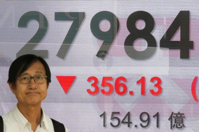 A man stands Thursday in front of an electronic board showing Hong Kong share index outside a bank in Hong Kong. Photo: Kin Cheung / Associated Press