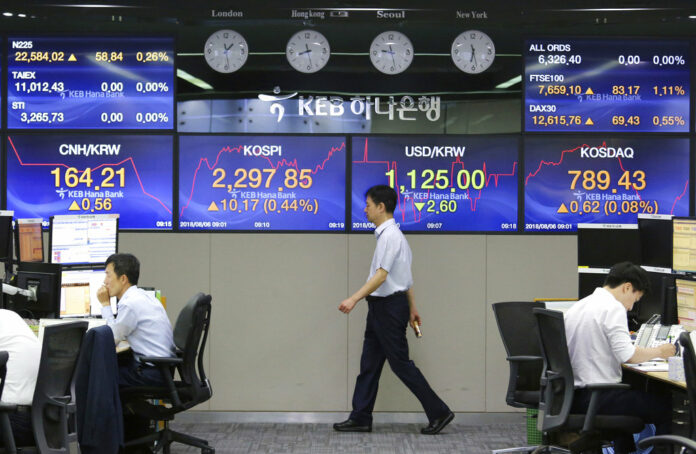 A currency trader walks by screens showing foreign exchange rates at the foreign exchange dealing room of the KEB Hana Bank headquarters Monday in Seoul, South Korea. Photo: Ahn Young-joon / Associated Press