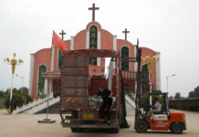 For God or Party? China’s Christians Face Test of Faith A worker jumps from a truck parked in front of a church and the Chinese national flag in June near the city of Pingdingshan in central China's Henan province. Photo: Ng Han Guan / Associated Press