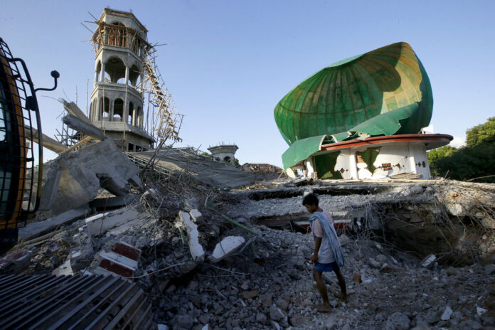 A resident on Tuesday inspects a mosque damaged by an earthquake in North Lombok, Indonesia. Photo: Tatan Syuflana / Associated Press