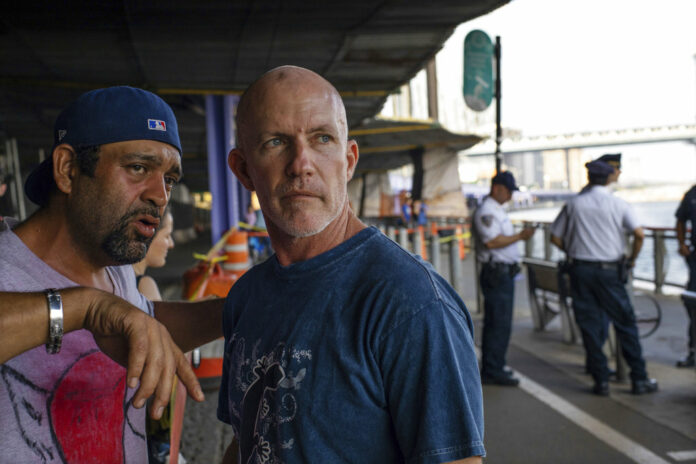 Monte Campbell, of Stillwater, Okla., right, stands under the Brooklyn Bridge in the Manhattan borough after jumping into New York's East River to rescue a baby floating in the East River. Photo: Robert Bumsted / Associated Press