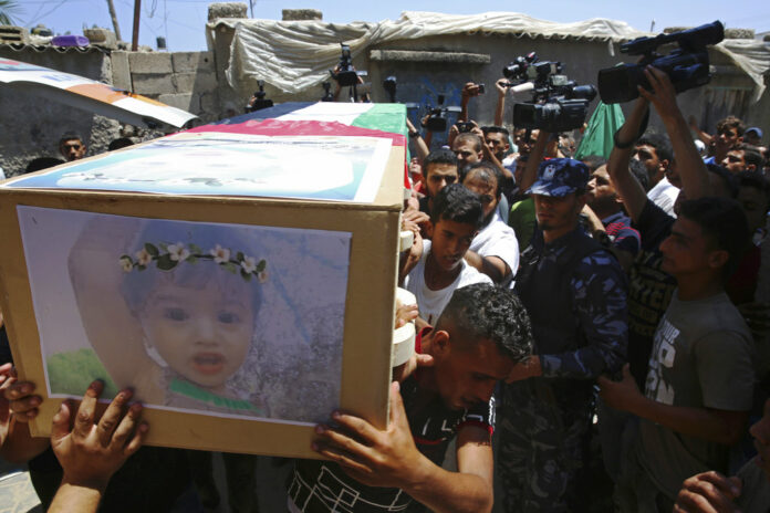 Palestinian mourners carry the coffin of 23-year-old pregnant mother Enas Khamash and her daughter Bayan, whose picture is on the coffin, Thursday during their funeral in Deir el-Balah, central Gaza Strip. Photo: Adel Hana / Associated Press
