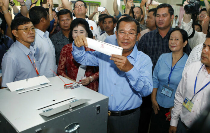 Cambodian Prime Minister Hun Sen, center, of the Cambodian People's Party (CPP), holds a ballot before voting July 29 at a polling station in Takhmua in Kandal province, southeast of Phnom Penh, Cambodia. Photo: Heng Sinith / Associated Press