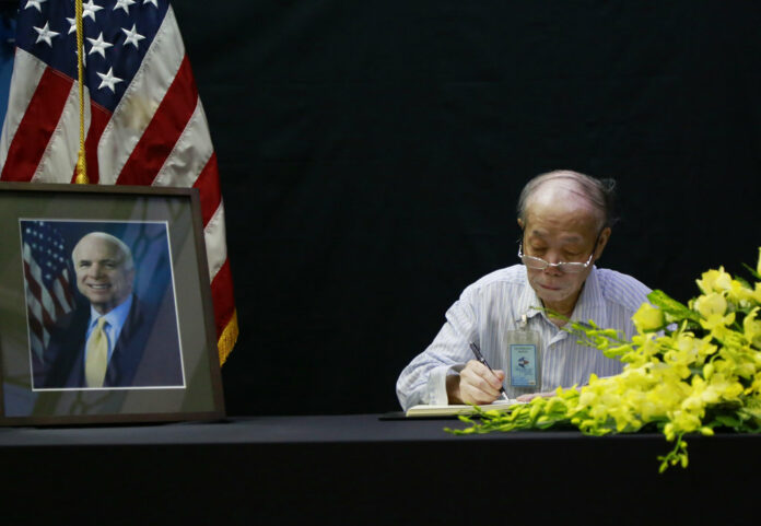 Pham Minh Chuc, an 81-year-old retiree, writes a book of condolences Monday for Senator John McCain in Hanoi, Vietnam. Photo: Tran Van Minh / Associated Press