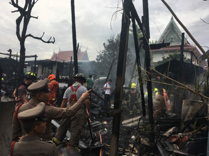 Police and firemen inspect the scene of a fire Friday morning that destroyed 16 homes in Bangkok's western district of Bangkok Yai.