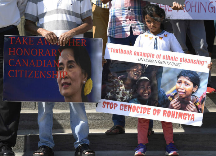 People hold signs against Myanmar leader Aung San Suu Kyi and the killing of the Rohingya people during a remembrance event to mark the one-year anniversary of the attacks that sent them fleeing to safety in Bangladesh, while holding a rally on Parliament Hill on Saturday in the Canadian capital of Ottawa. Photo: Justin Tang / The Canadian Press via AP