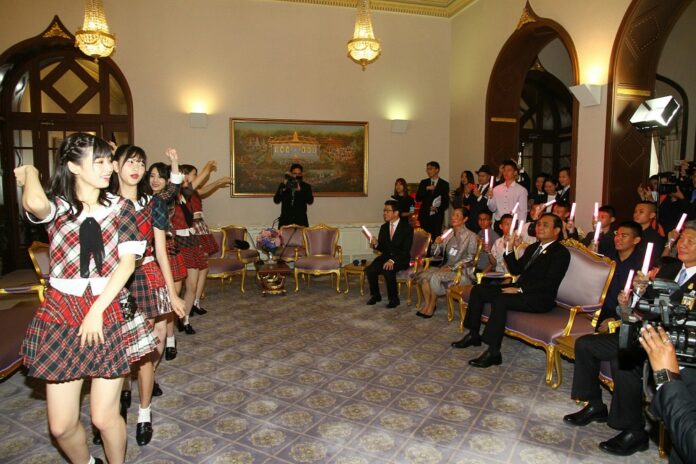 Junta chairman Prayuth Chan-ocha waves his glow stick Thursday while six members of AKB48 perform per his request.