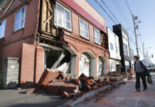 Quake in Northern Japan Kills 2, Causes Landslides, Blackout A woman walks past a damaged building Thursday in Abira town, near Chitose, Hokkaido, northern Japan. Photo: Masanori Takei / Associated Press