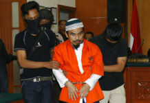 Indonesian Court Rules Militant Guilty of Extremism Islamic militant Wawan Kurniawan, center, is escorted by masked police officers upon arrival for his Thursday trial at West Jakarta District Court in Jakarta, Indonesia. Photo: Tatan Syuflana / Associated Press