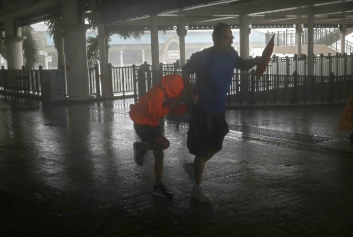 A man and a girl walk against strong winds from Typhoon Mangkhut on a pier on Victoria Habour Hong Kong, Sunday, Sept. 16, 2018. Photo: Vincent Yu / Associated Press