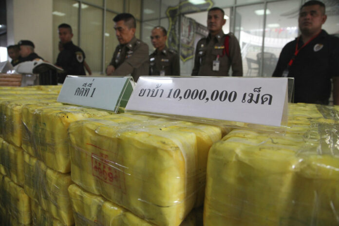 Policemen stand in front of seized methamphetamine pills at the Narcotics Suppression Bureau during a Tuesday press conference in Bangkok. Photo: Associated Press