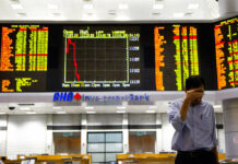 Asian Shares Mostly Up Cheered by Wall Street Buying Spree An investor walks in front of trading boards at a private stock market gallery in September in Kuala Lumpur, Malaysia. Photo: Yam G-Jun / Associated Press