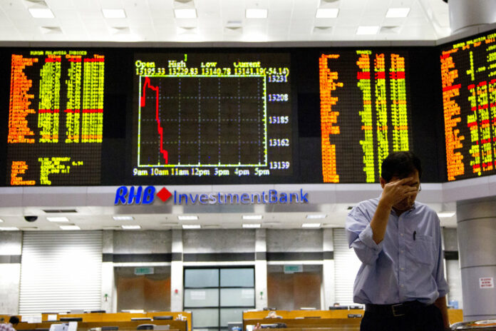 An investor walks in front of trading boards at a private stock market gallery in September in Kuala Lumpur, Malaysia. Photo: Yam G-Jun / Associated Press