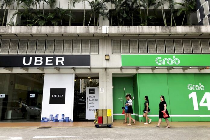 A 2018 file photo of office workers walking past Uber and Grab offices during their lunch hour in Singapore. Photo: Wong Maye-E / Associated Press