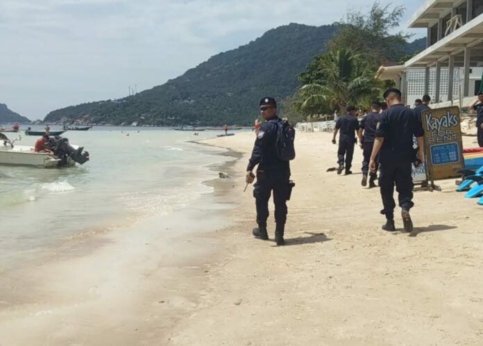 Police walk along a beach on Koh Tao, Sept. 1, 2018.