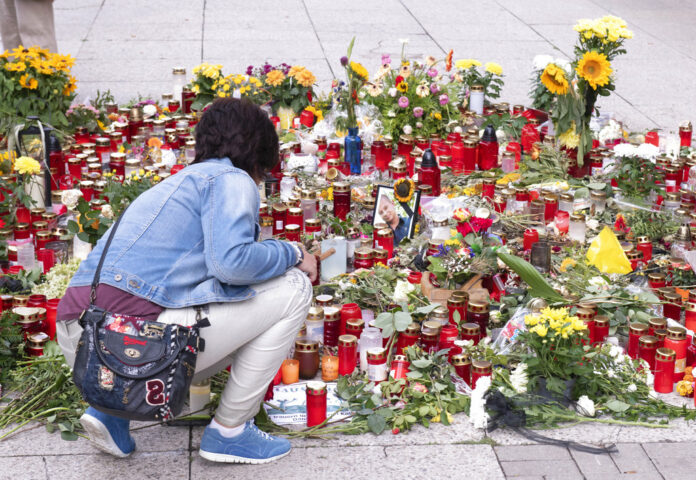 A woman kneels in front of candles and flowers Friday at the scene of an earlier altercation in Chemnitz, Germany. Photo: Jens Meyer / Associated Press