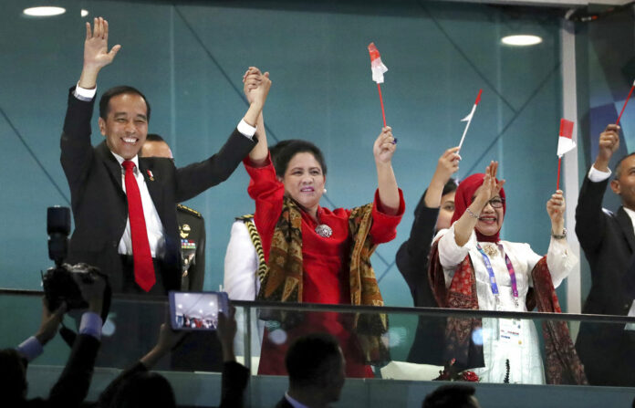 Indonesian President Joko Widodo, left, and his wife Iriana wave during the Aug. 18 opening ceremony for the 18th Asian Games in the Gelora Bung Karno Stadium in Jakarta. Photo: Dita Alangakara / Associated Press
