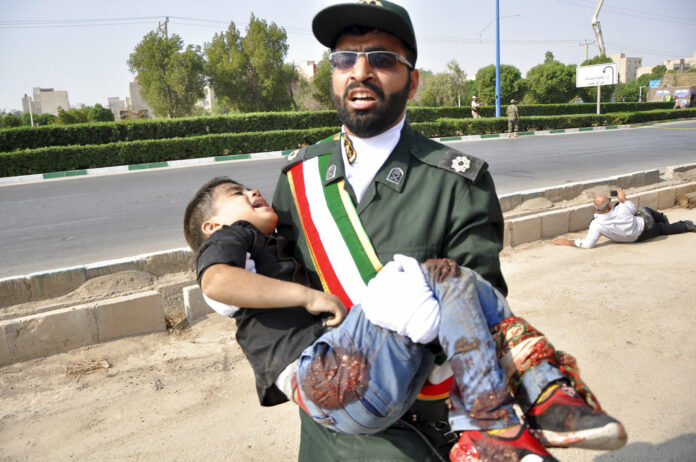 In this photo provided by the Iranian Students' News Agency, ISNA, a Revolutionary Guard member carries a wounded boy after a shooting during a military parade marking the 38th anniversary of Iraq's 1980 invasion of Iran, in the southwestern city of Ahvaz, Iran, Saturday, Sept. 22, 2018. Gunmen attacked the military parade, killing at least eight members of the elite Revolutionary Guard and wounding 20 others, state media said. Photo: Behrad Ghasemi / ISNA via AP
