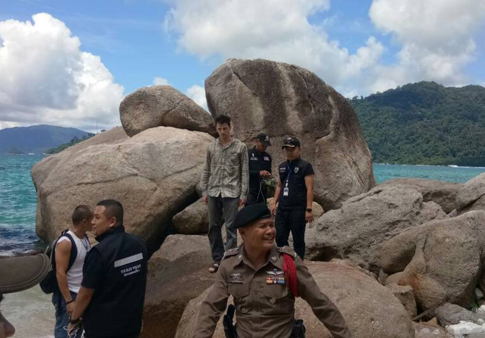 Police lead Charles Kosydar away Thursday from a pile of rocks where he sought solitude on Koh Lipe's Sunset Beach.