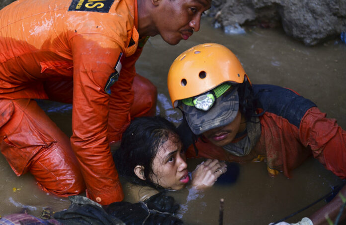 Rescuers evacuate an earthquake survivor by a damaged house Sunday following earthquakes and tsunami in Palu, Central Sulawesi, Indonesia. Photo: Arimacs Wilander / Associated Press Rescuers evacuate an earthquake survivor by a damaged house Sunday following earthquakes and tsunami in Palu, Central Sulawesi, Indonesia. Photo: Arimacs Wilander / Associated Press