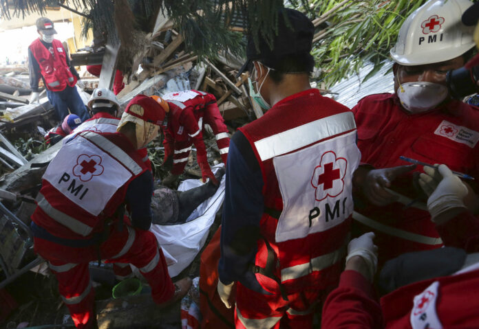 Indonesian red cross team carry the body of a tsunami victim following a massive earthquake and tsunami Monday at Talise beach in Palu, Central Sulawesi, Indonesia. Photo: Tatan Syuflana / Associated Press